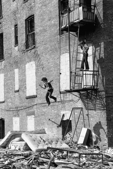 Una fotografía de una obra callejera de Martha Cooper de un niño saltando de una escalera de incendios en el Lower East Side.