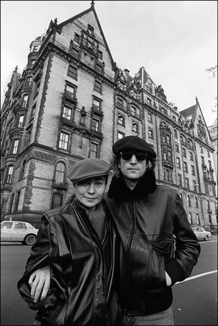Black and white photo of Yoko Ono, left, and John Lennon, right in front of the Dakota apartment building.