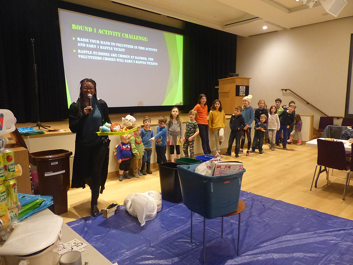 Photograph of participants separating waste into appropriate trash bins based on what recyclable material they are made from. 