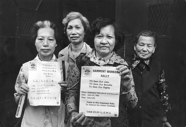 Cuatro miembros del ILGWU Local 23-25 ​​que están en huelga sostienen volantes en chino e inglés para el mitin del 24 de junio de 1982.