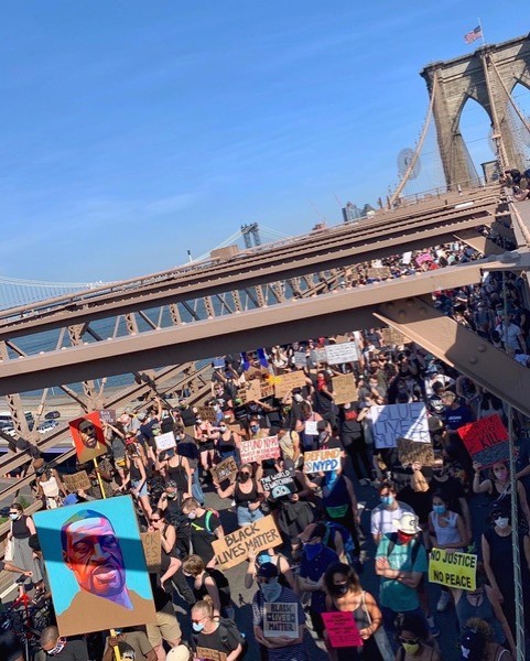 Un groupe de manifestants sur le pont de Brooklyn avec divers signes.