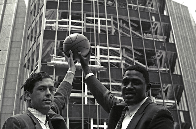 Bill Bradley y Willis Reed sostienen una pelota de baloncesto en el aire junto al sitio de construcción del Madison Square Garden.