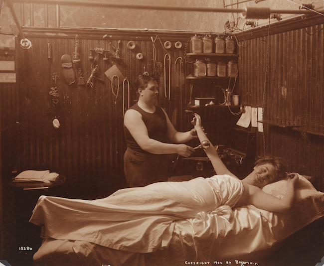 Una mujer descansando, recibiendo una especie de terapia de masaje en un baño turco.