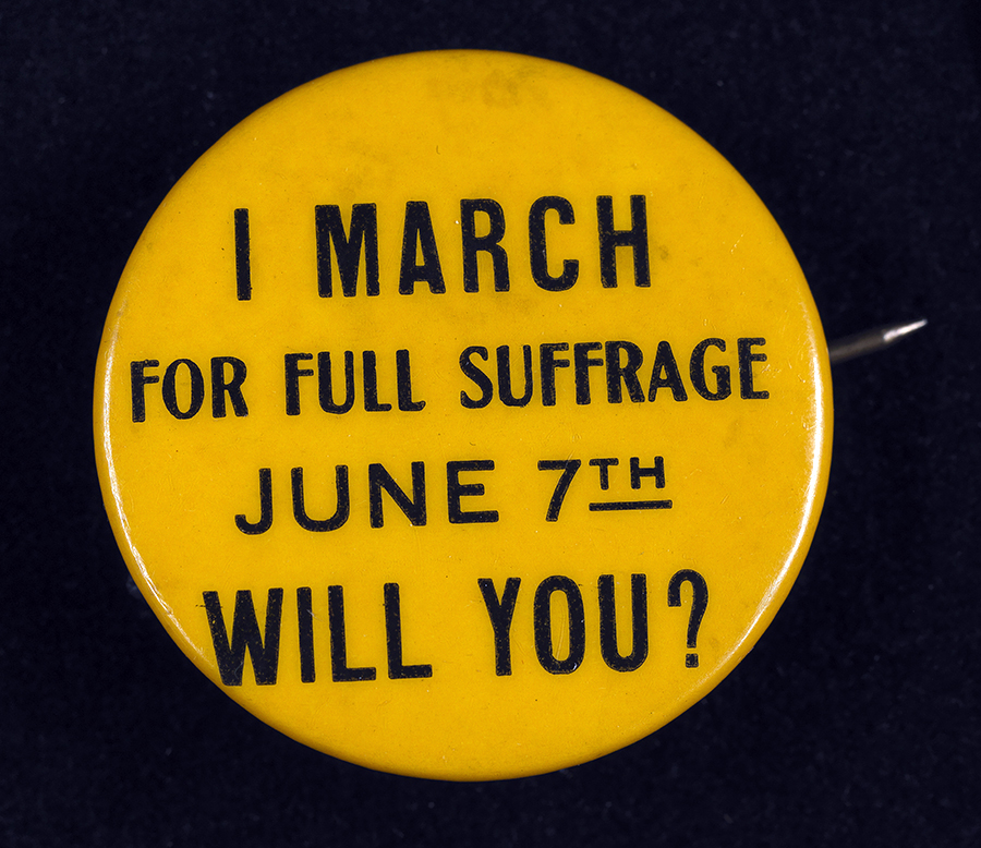 Un petit bouton en or soutenant le droit de vote des femmes du début du 20e siècle se lit comme suit: Je marche pour le suffrage complet le 7 juin. Vas-tu?