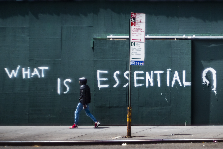 Un homme passe devant un mur barré avec les mots «Ce qui est essentiel» peint à la bombe dessus.