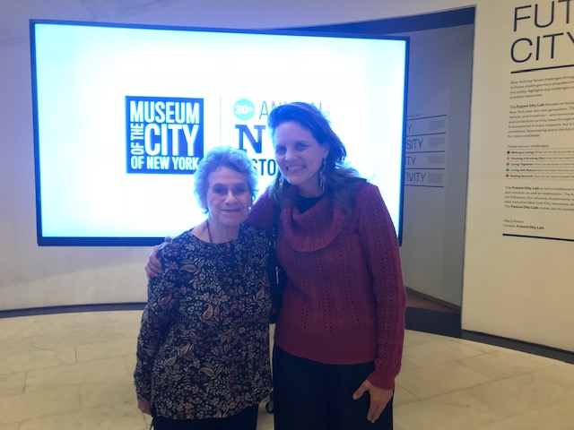 박물관과 역사의 날 로고가있는 스크린 앞에 두 명의 여성이 함께 서 있습니다.