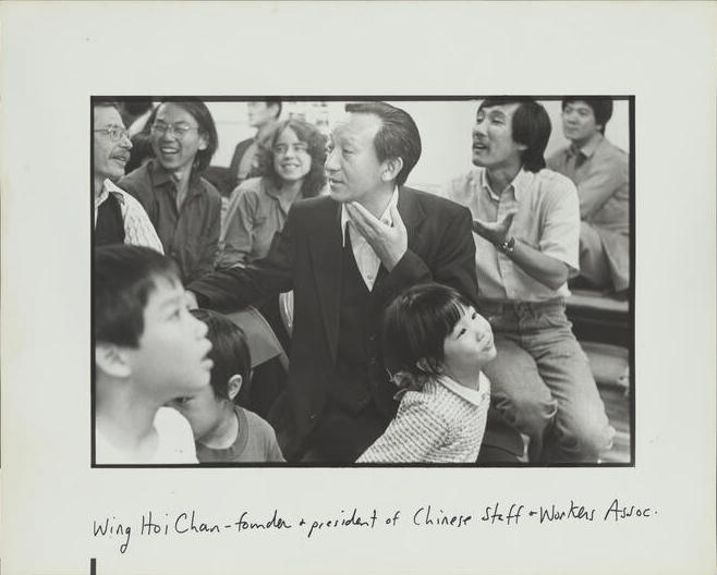 Wing Hoi Chan se sienta en el centro de un grupo de adultos y niños.