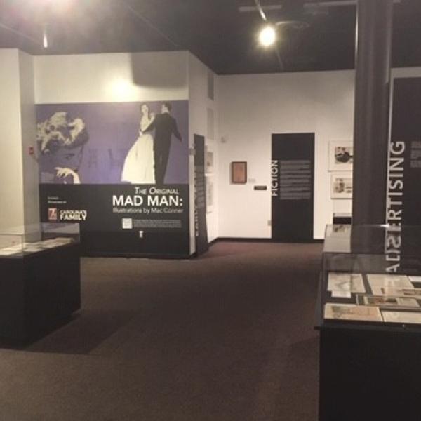 Una fotografía de instalación de exhibición de The Original Mad Man: Ilustraciones de Mac Conner.