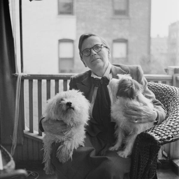 Florence Ripley Mastin assise sur un porche avec deux chiens sur ses genoux.