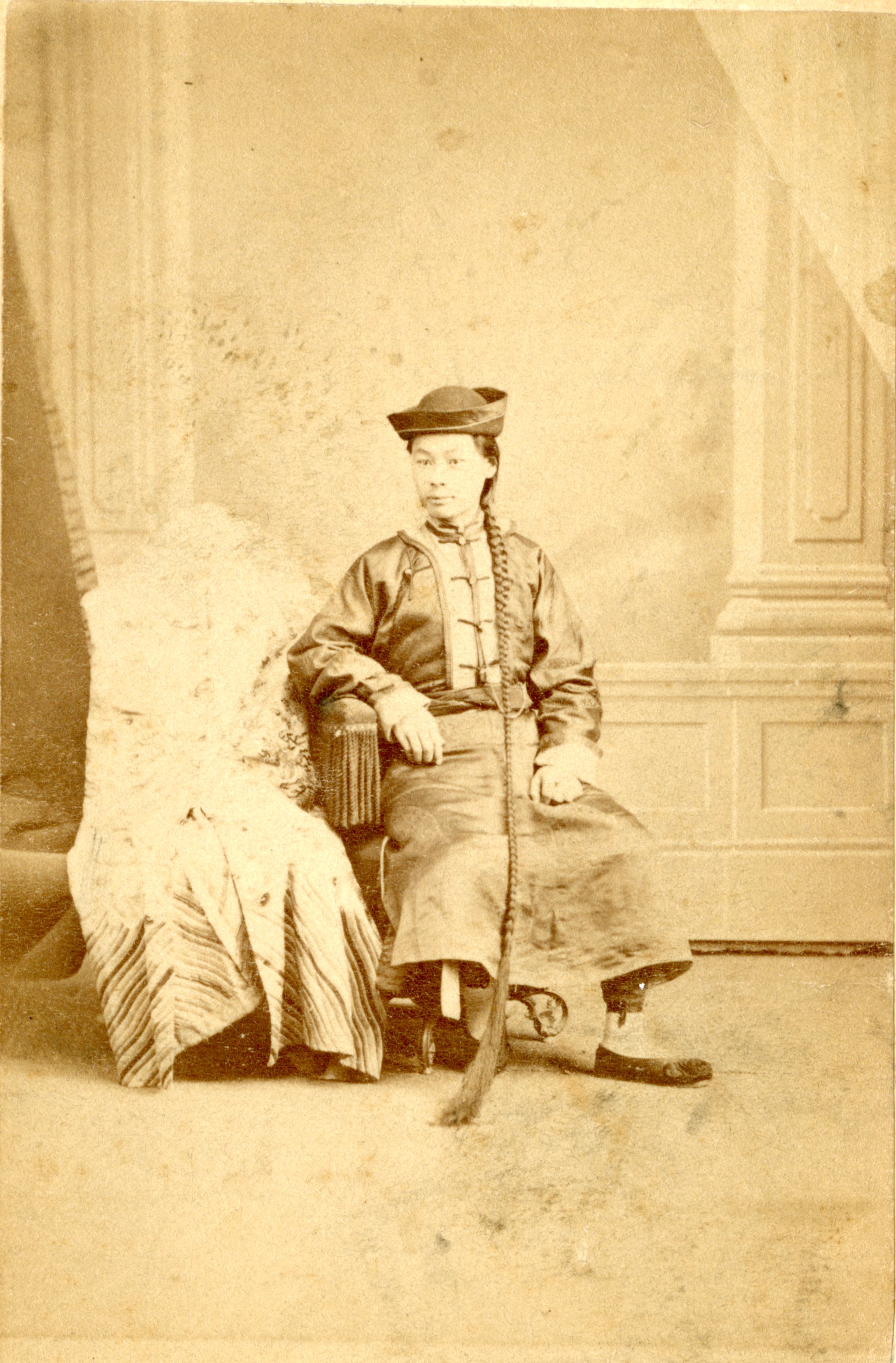 A woman in traditional clothing poses in a chair.