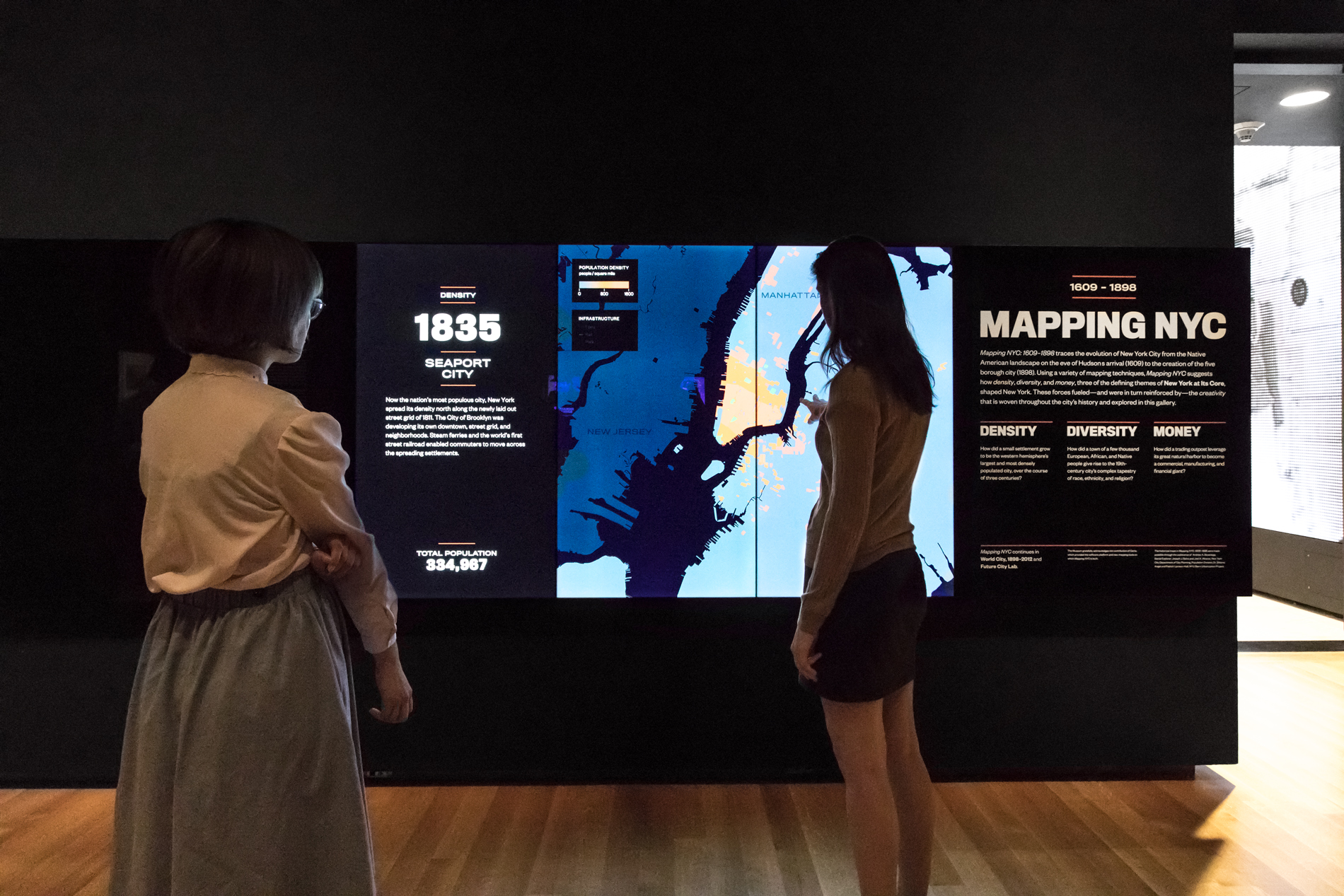 Two visitors look at a changing screen on display in a gallery