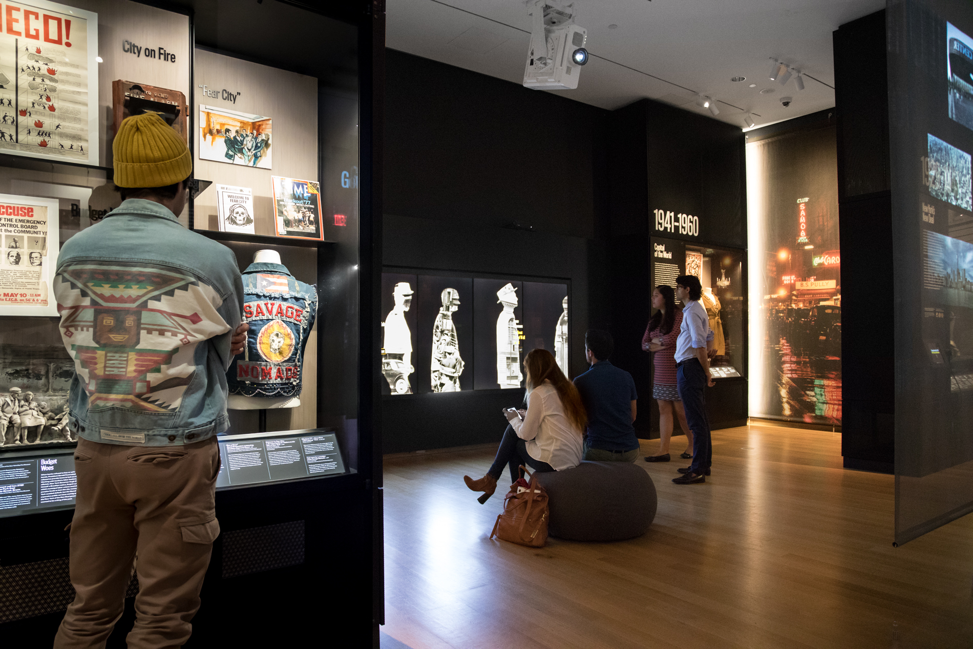 Visitors look at objects on display and interactive digital components in an exhibition