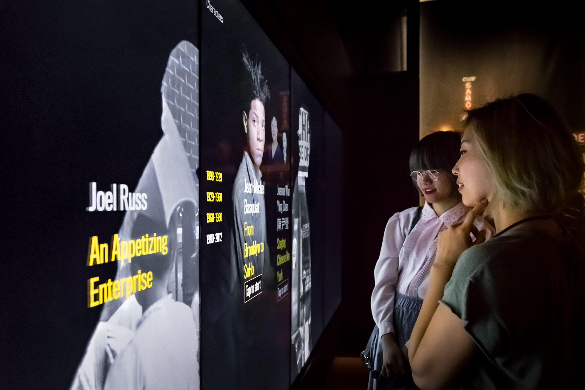 Dois visitantes visualizam telas interativas em exibição em uma galeria