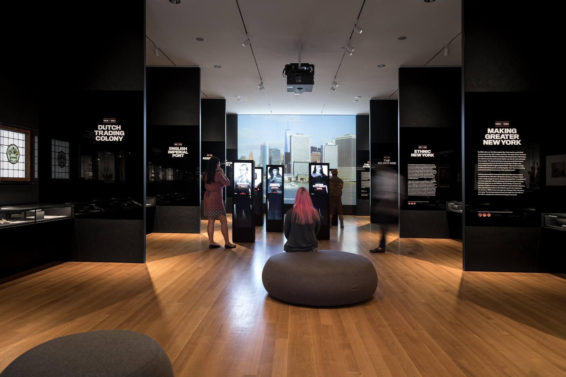 Visitors sit and stand around an exhibition at the Museum of the City of New York