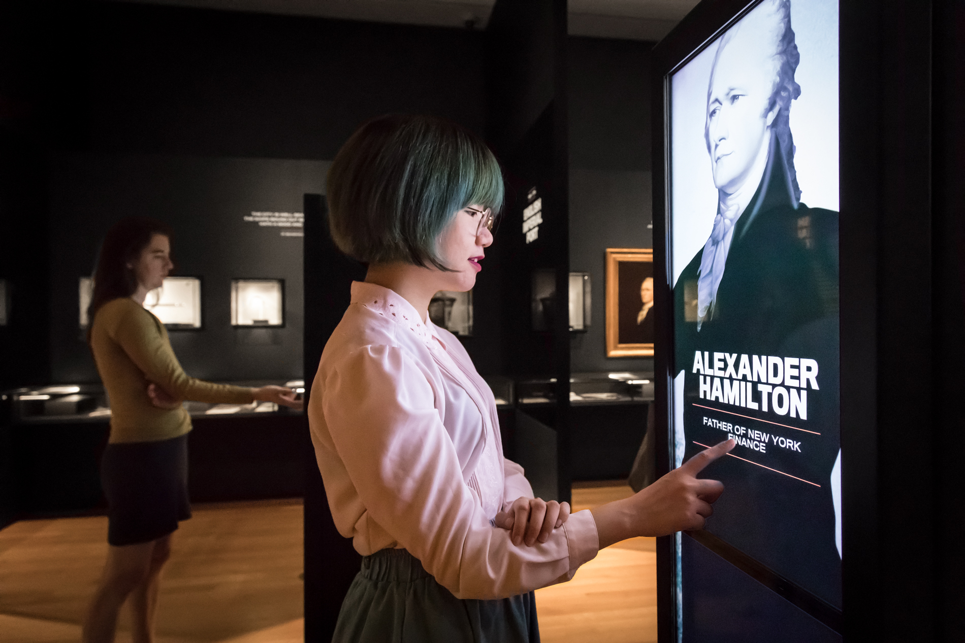 Two visitors examine an interactive feature in an exhibition space