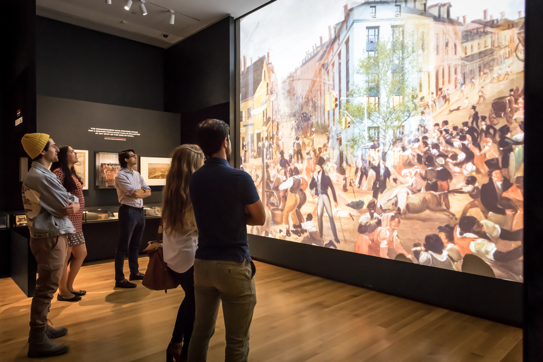 Los visitantes miran una gran proyección en un espacio de exhibición