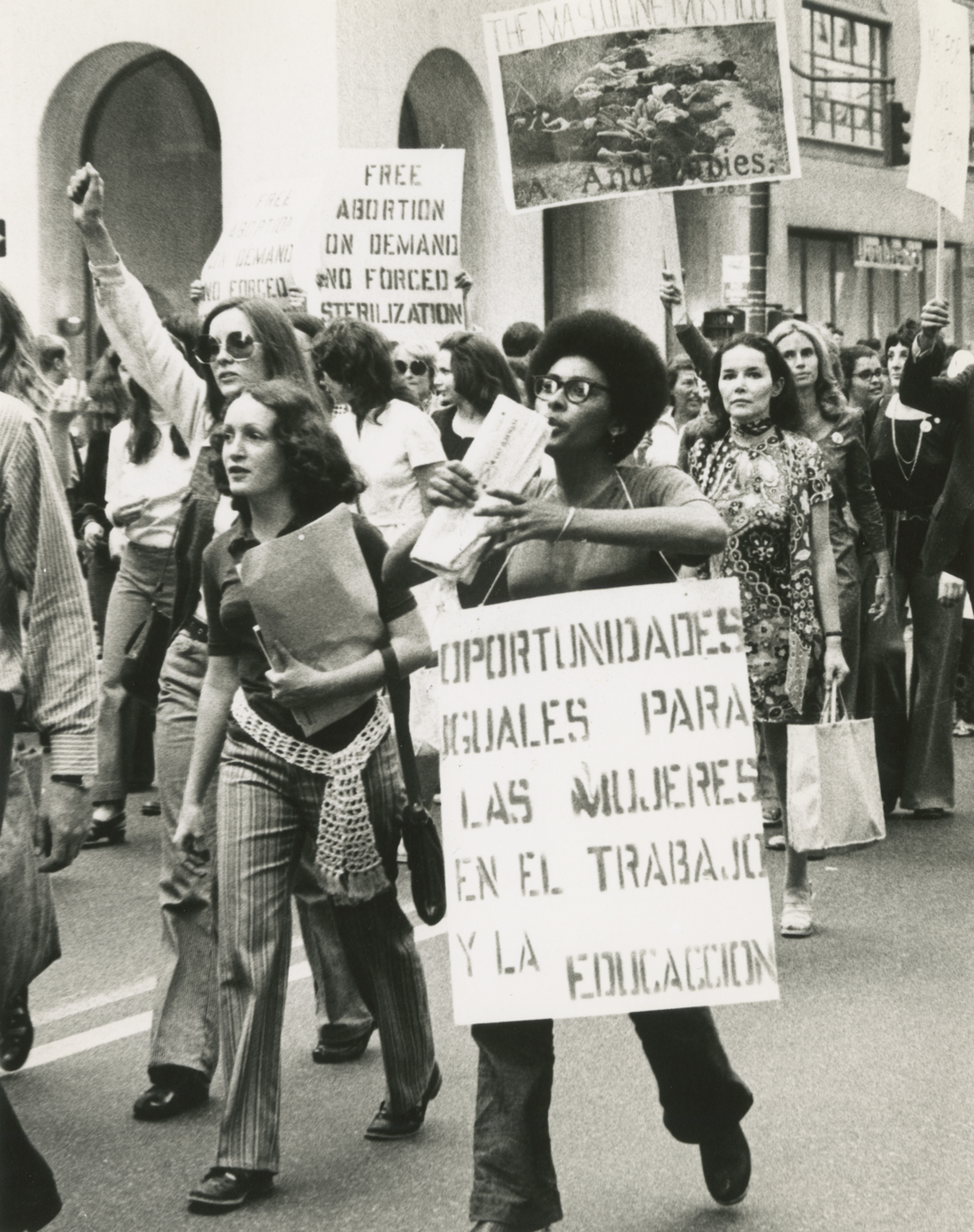 Un groupe de femmes marchent dans un rassemblement, beaucoup tiennent des pancartes de protestation
