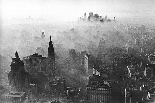 Black and white aerial shot of Midtown and Lower Manhattan. The skyline is obscured by a thick smog.