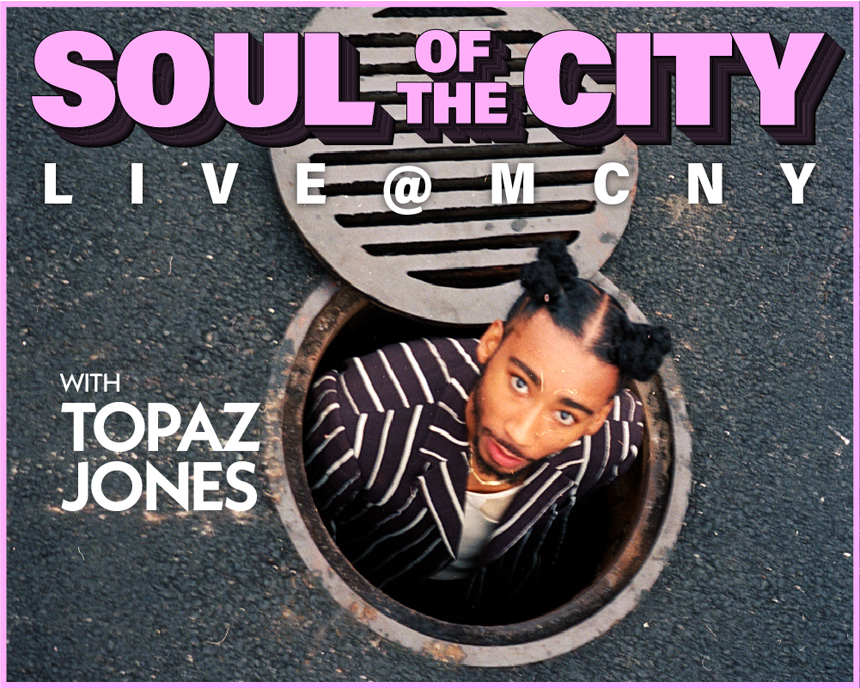 하수구 안에 있는 동안 토파즈 존스가 카메라를 올려다보고 있습니다. 이미지 상단에는 "Soul of the City: Live @ MCNY with Topaz Jones"라는 텍스트가 있습니다.