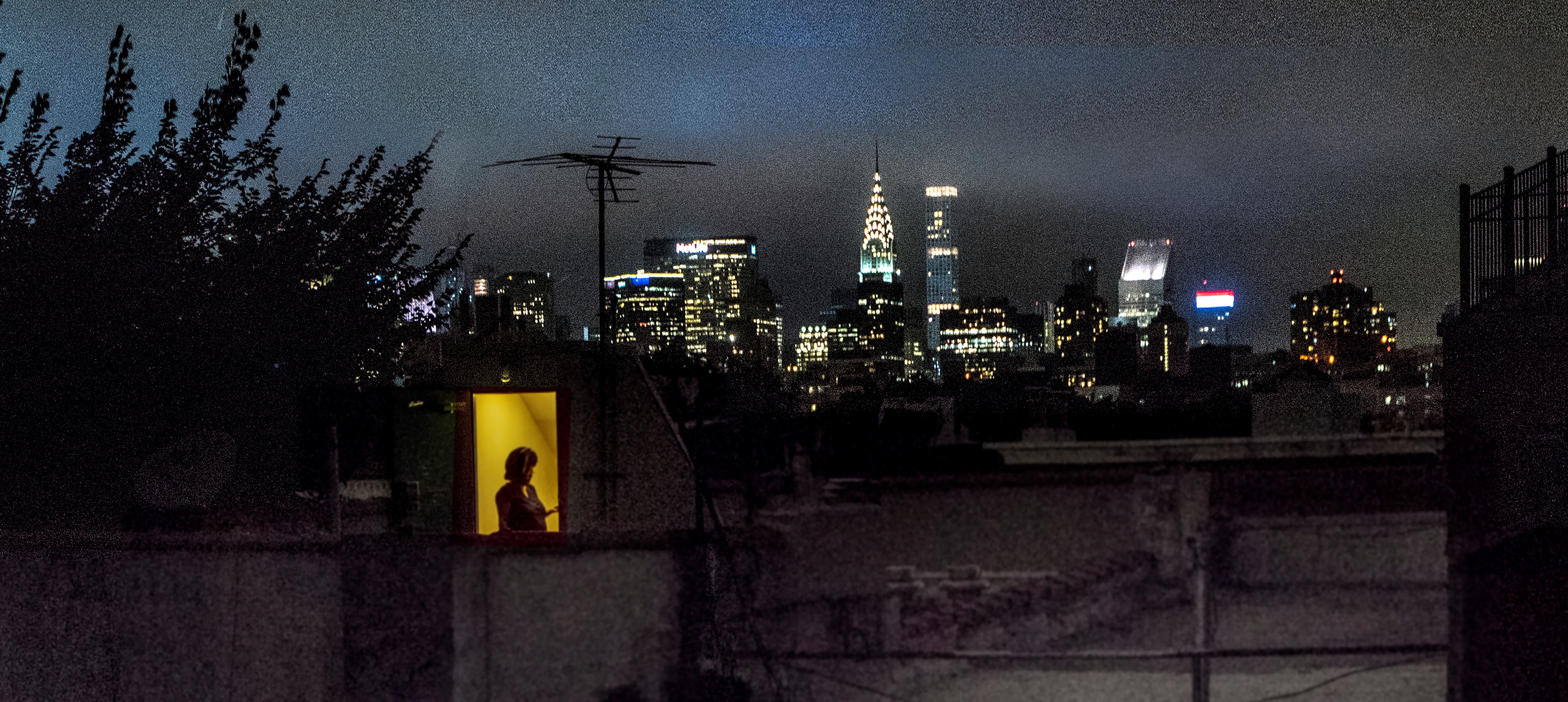 Vista trasera del apartamento de Sally Davies en East 5th Street por la noche con ventanas iluminadas.