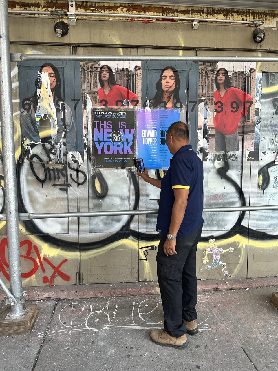 Man stops to use QR code on wild postings for the exhibition "This Is New York"