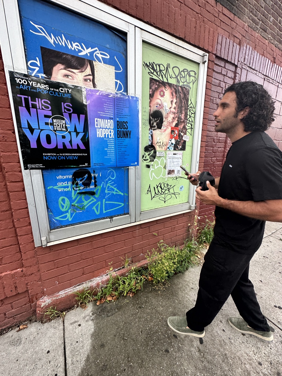 Man views wild postings for the exhibition This Is New York