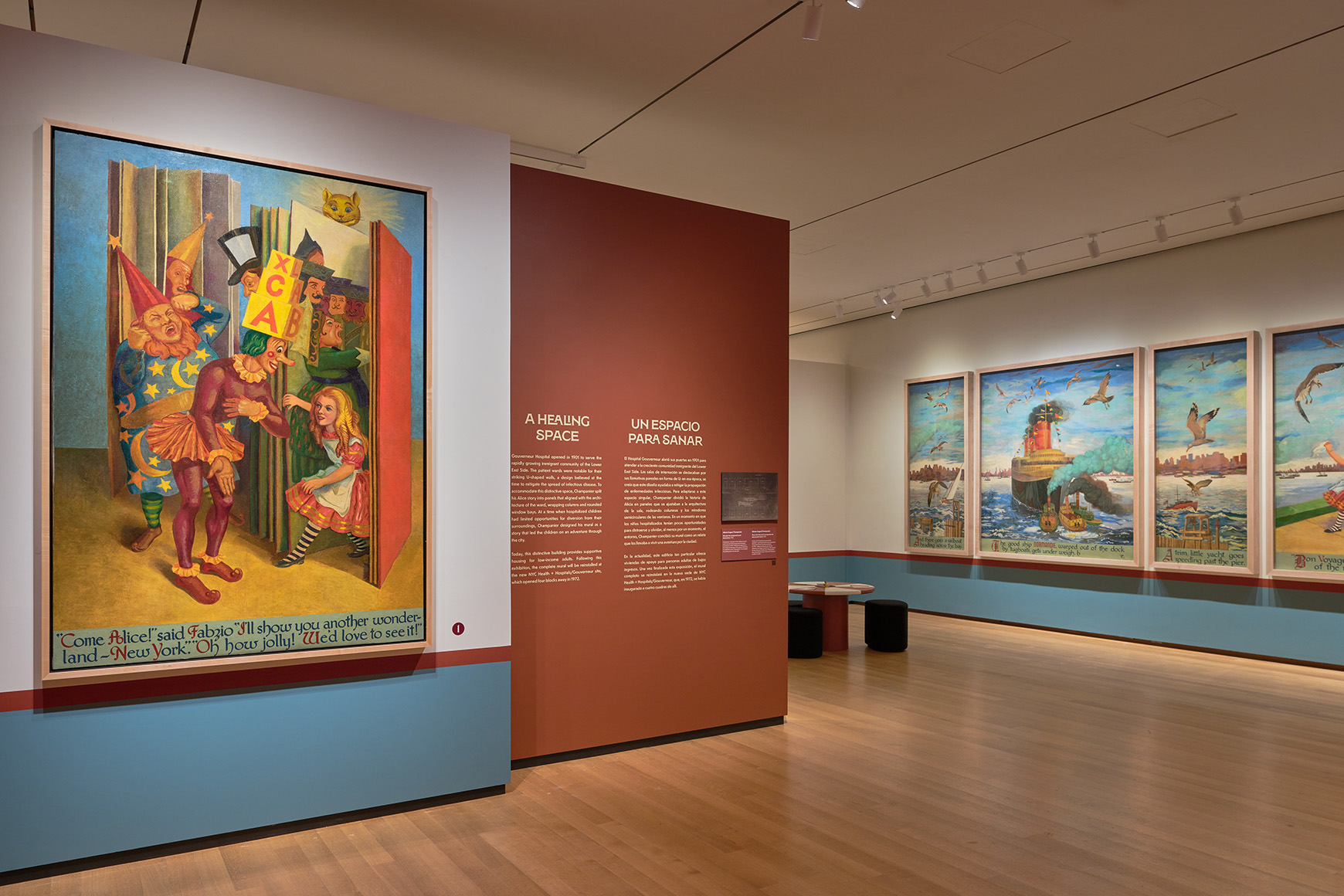 Large mural panels showing Alice and other characters exploring New York City, with red and white tables in the middle of the gallery.