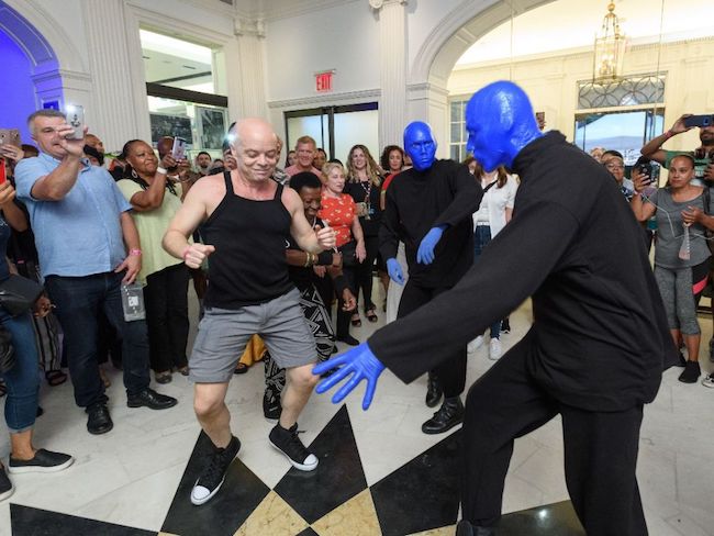 Trois hommes bleus (du groupe Blue Man) dansent dans le hall du musée avec les visiteurs pendant Uptown Bounce en août 2019.