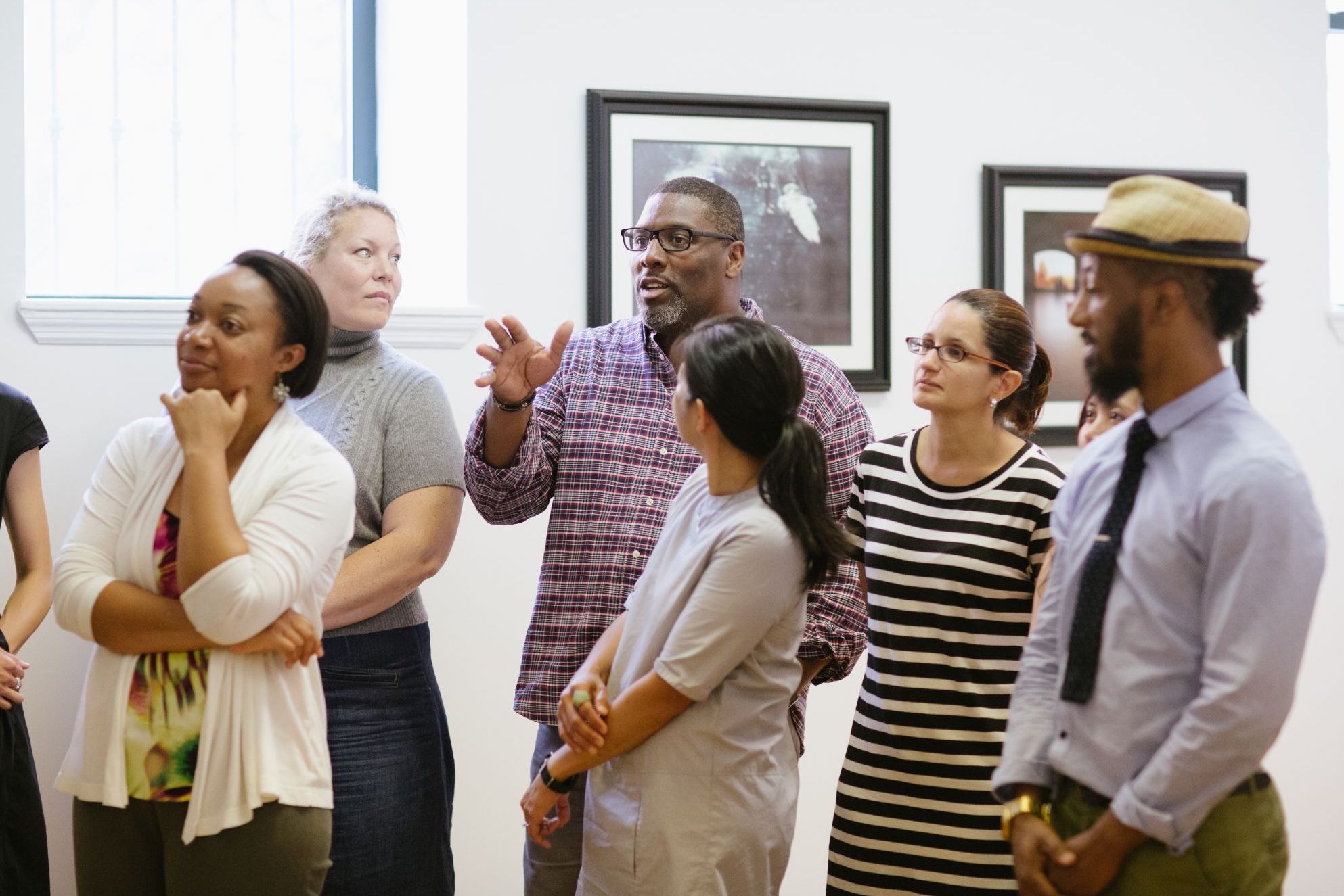 A group of adults stand together in a gallery. 