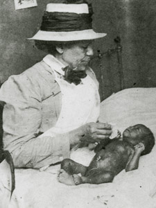 Enfermeira afro-americana do assentamento de Henry Street visita mãe e bebê, na Califórnia. 1910