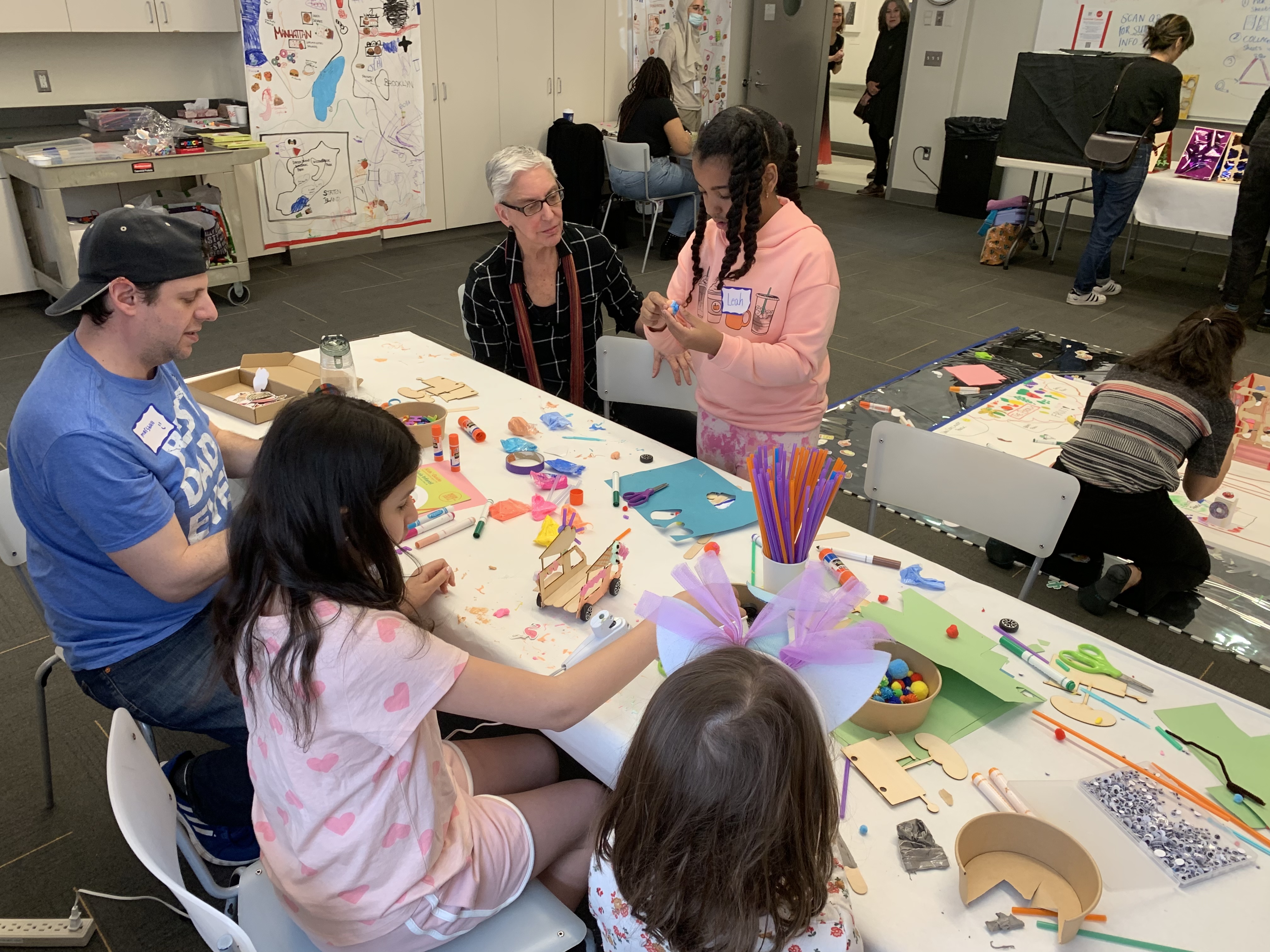 An image of families sitting around a table and working on a shared project