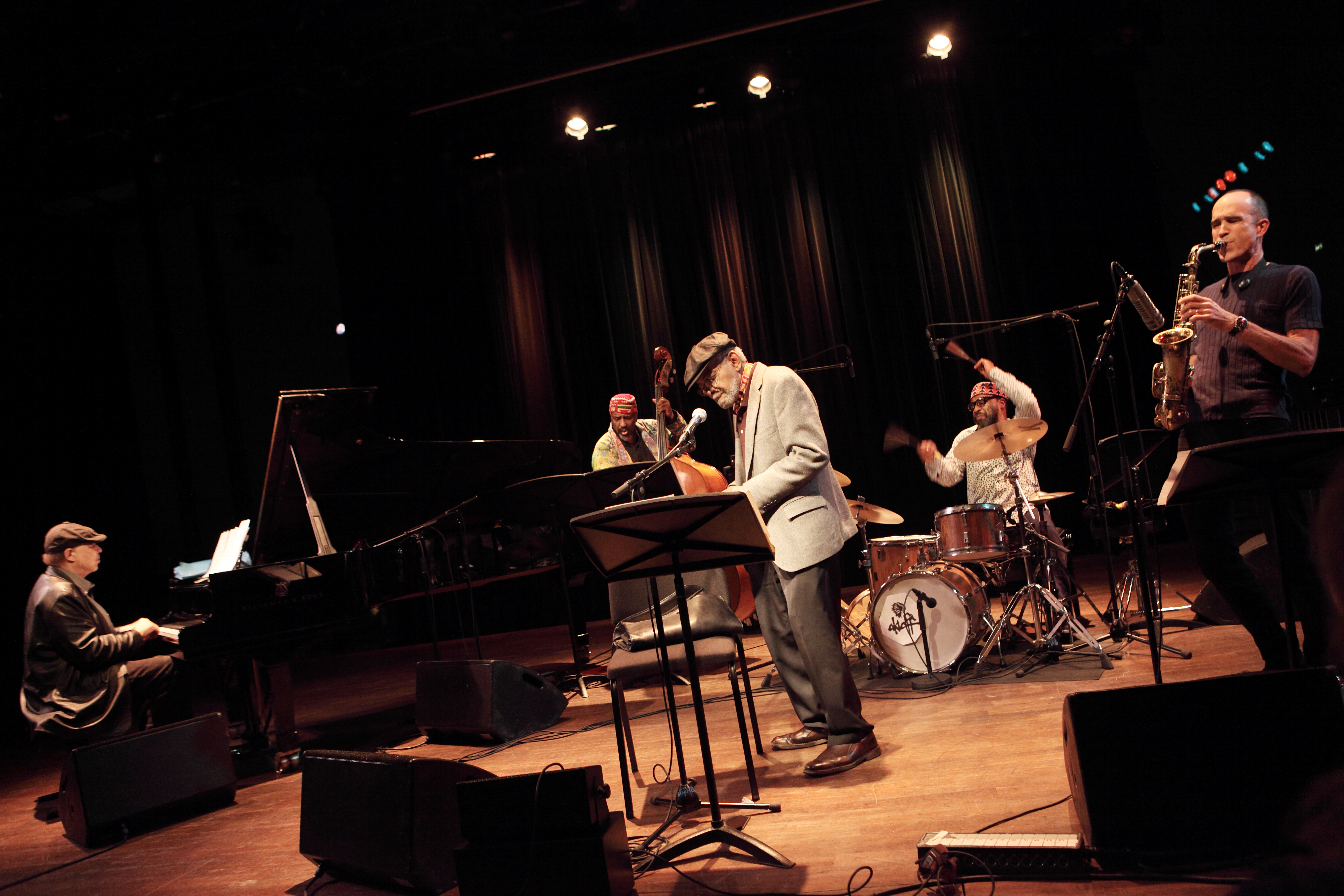 El poeta Amiri Baraka actuando con un grupo de músicos de jazz en un escenario.