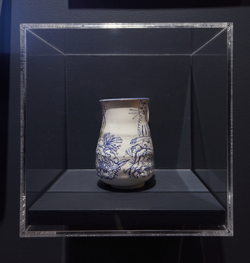 Mug en céramique blanche à motifs floraux bleus. Un dessin d'un chat est visible sur le côté droit.