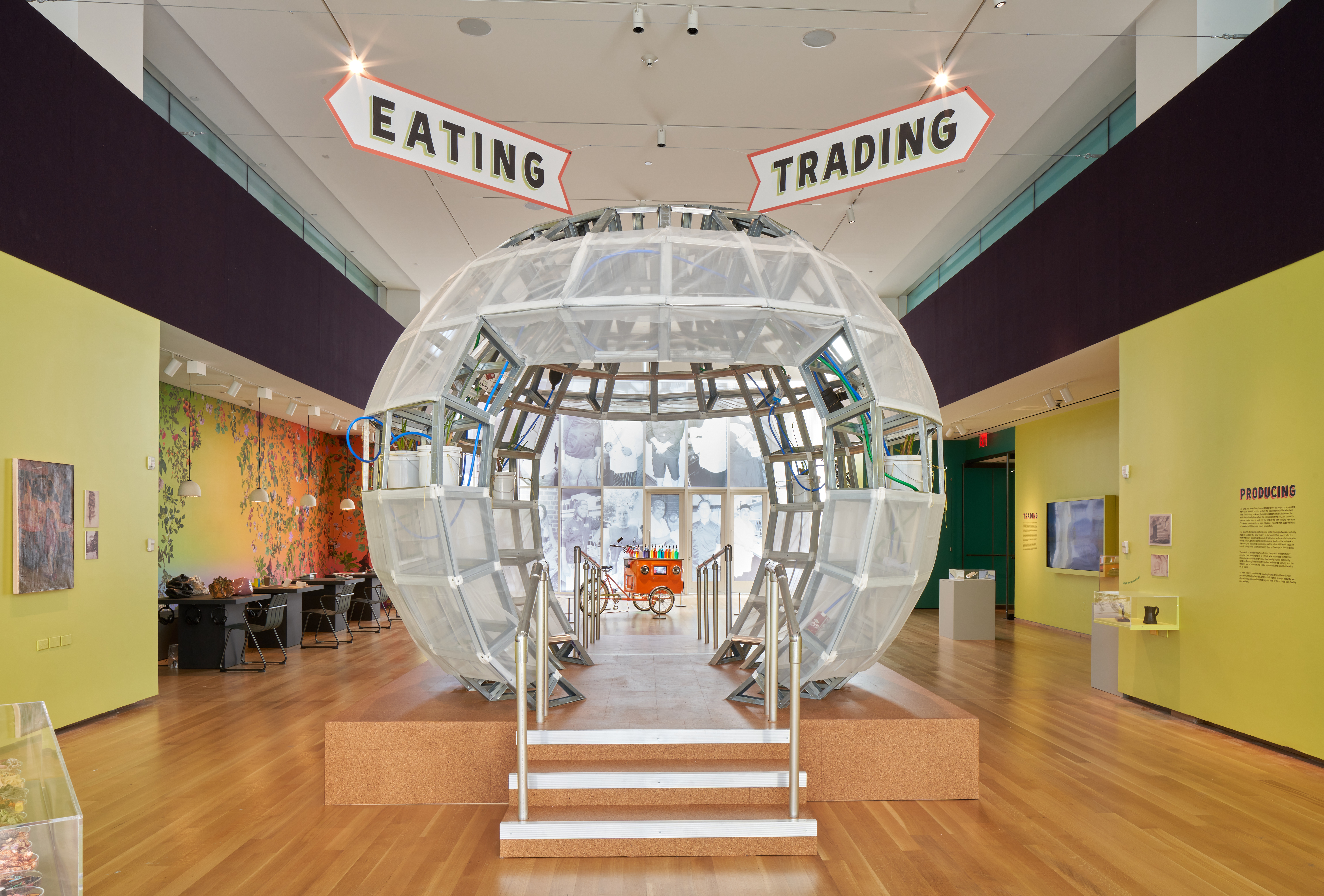 A large clear sphere, similar to a snowglobe sits at the center of the image with signs that read 'eating' and 'trading' above it. 