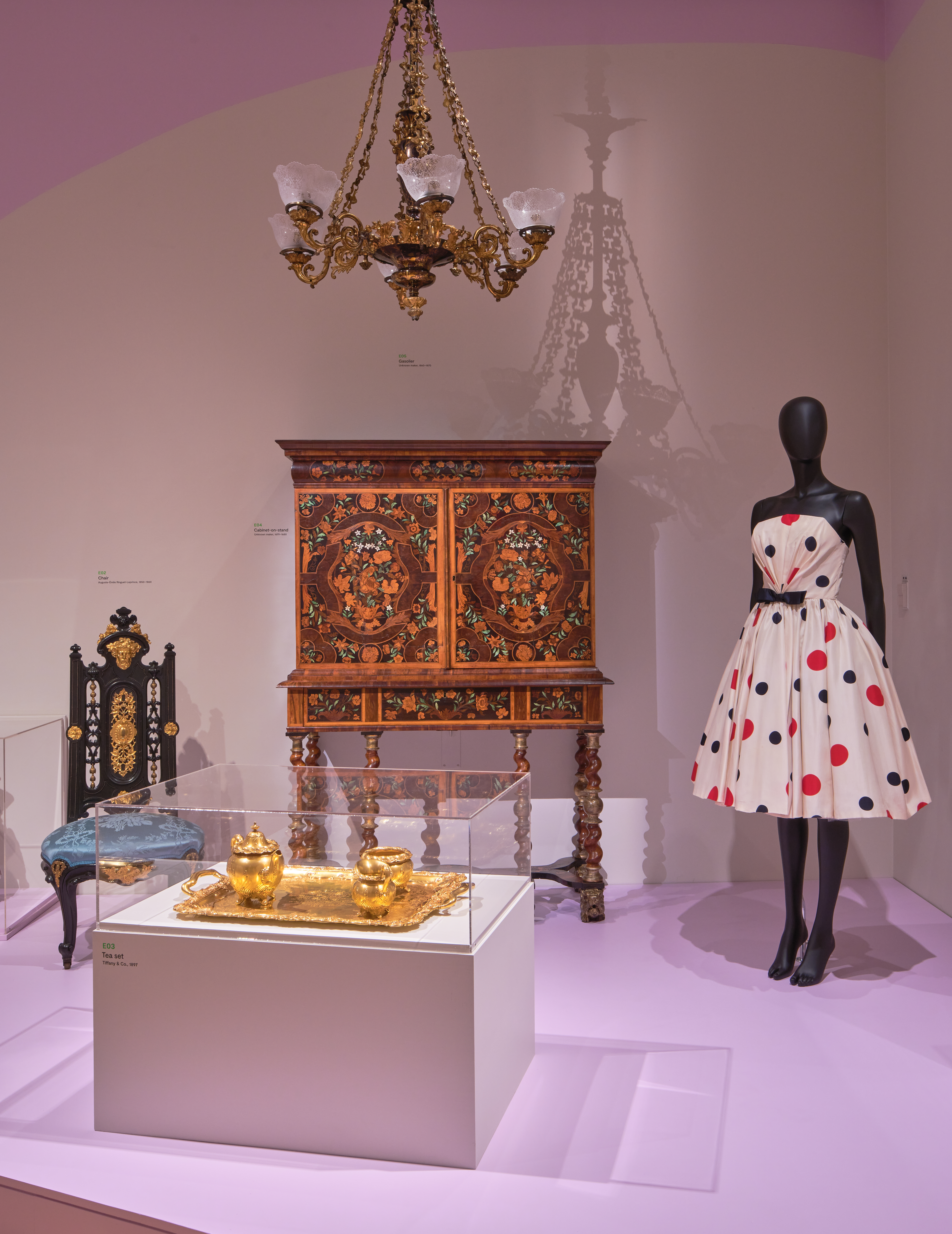 Un mannequin et des meubles ornés sont exposés dans une galerie.