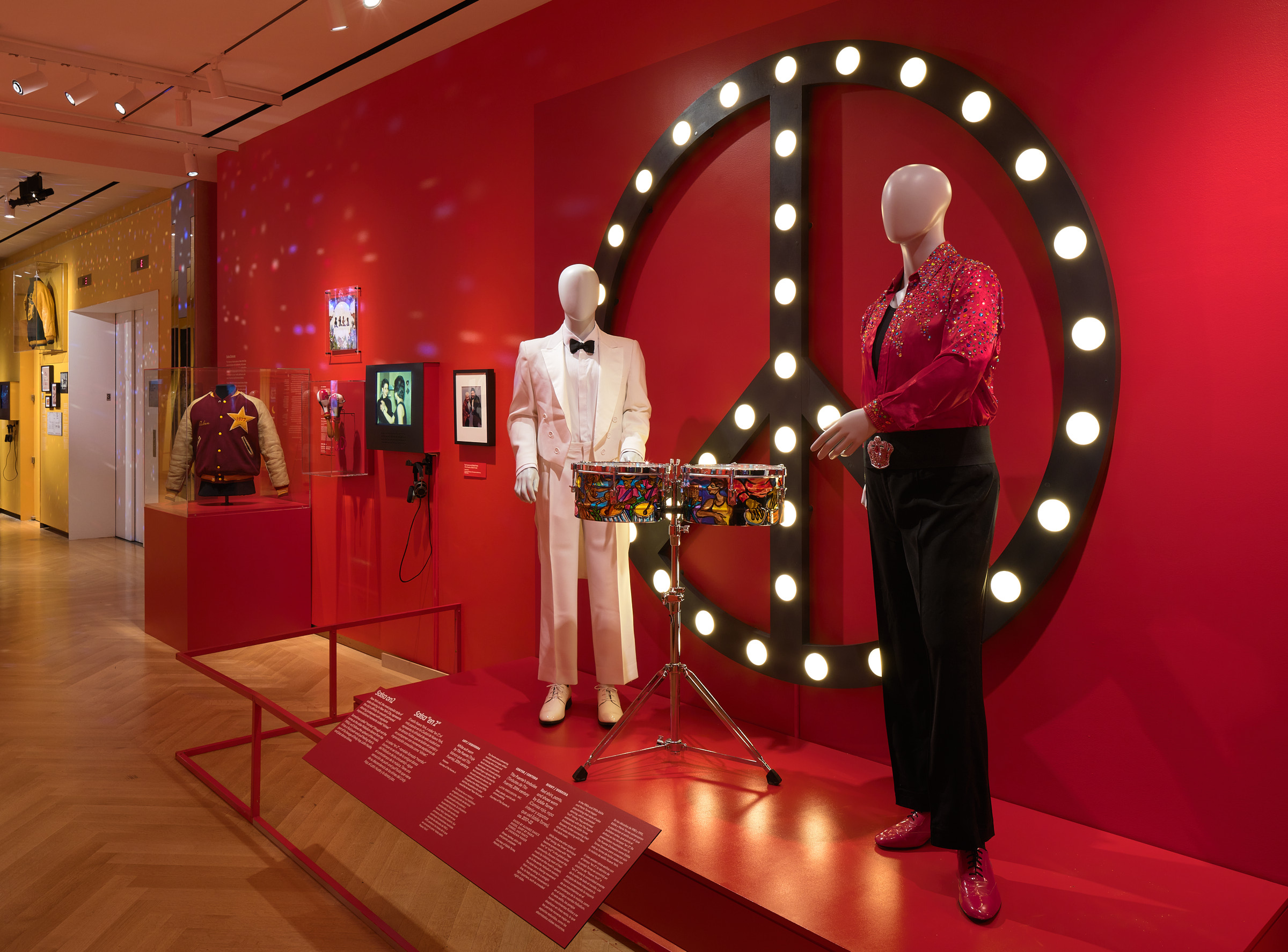 Manequins vestindo roupas festivas em frente a um sinal de paz