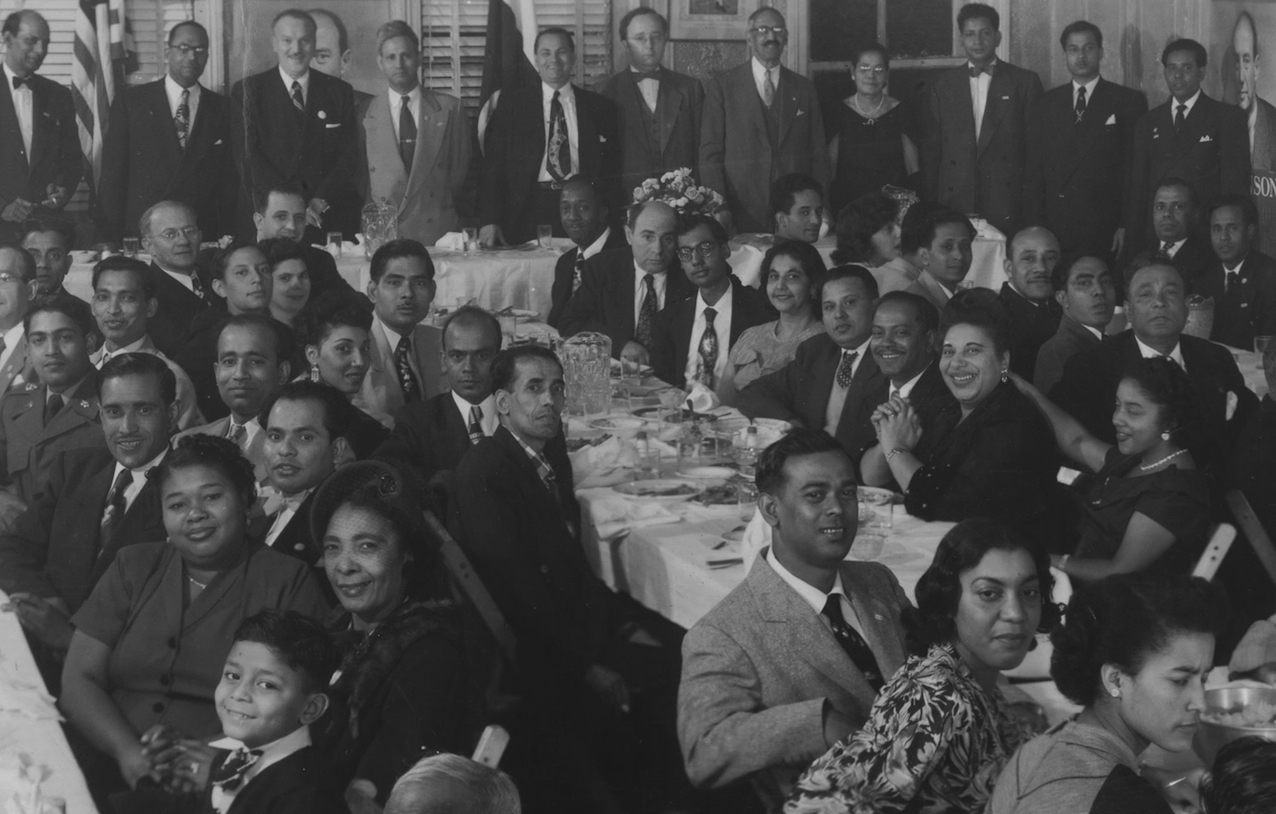 큰 테이블 주위에 앉아 있는 그룹의 흑백 이미지