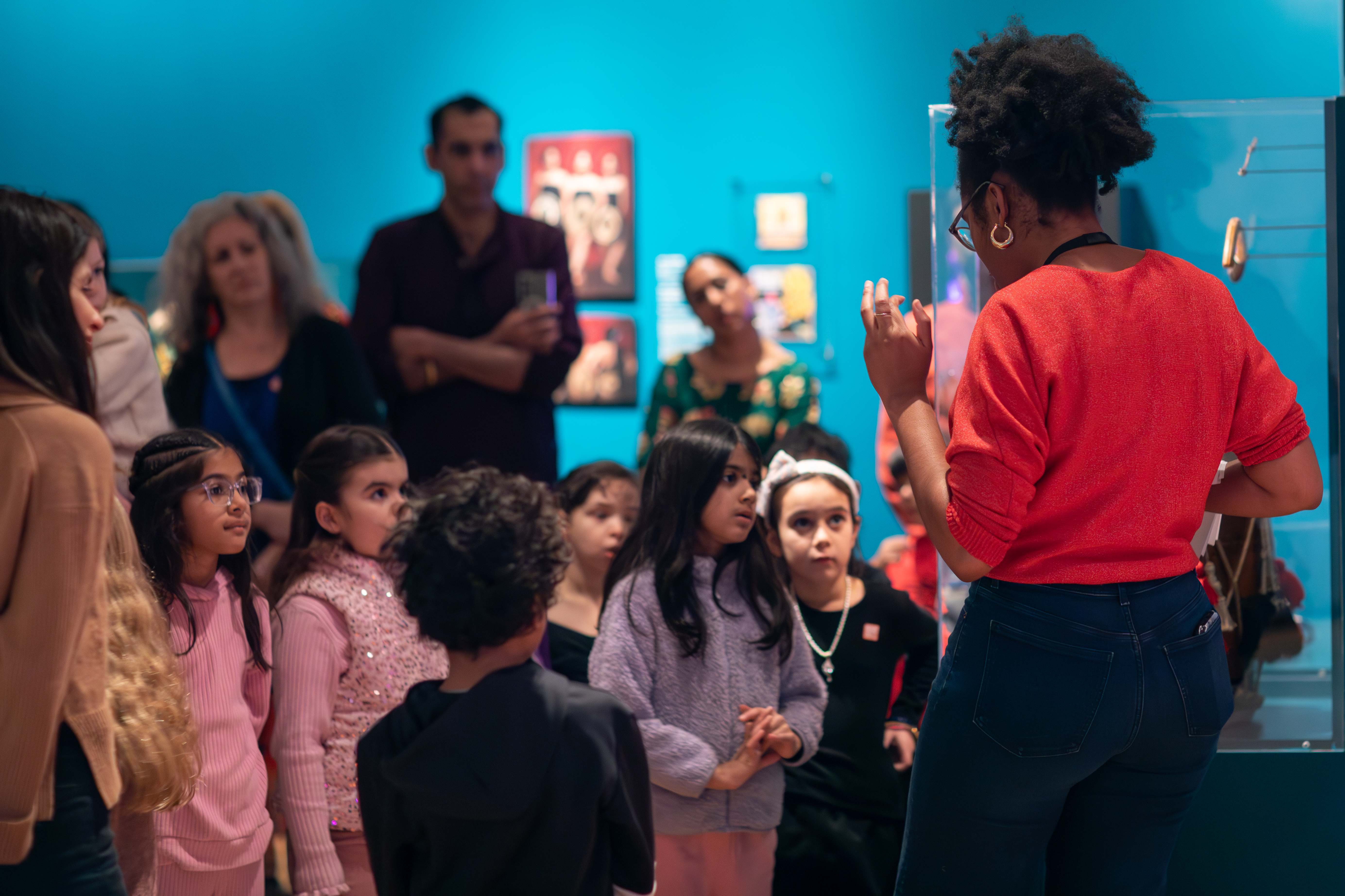 Image of children looking closely in a single direction with adults blurred in the background
