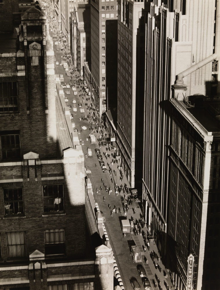 View of a street in New York City that’s surrounded on both sides by tall buildings, creating a “canyon” with the street