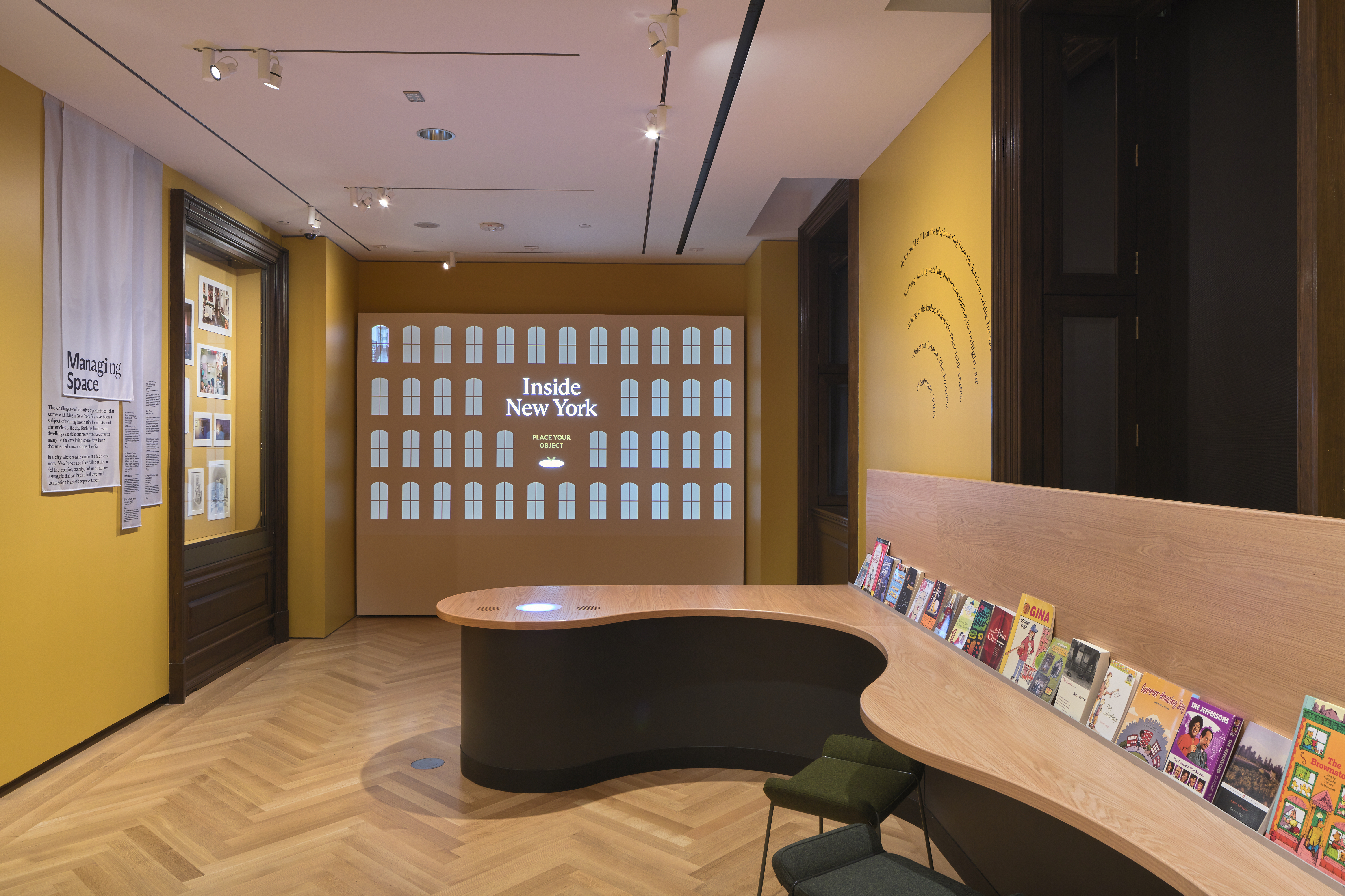 A wall display in a gallery with books lined up on a wall. 