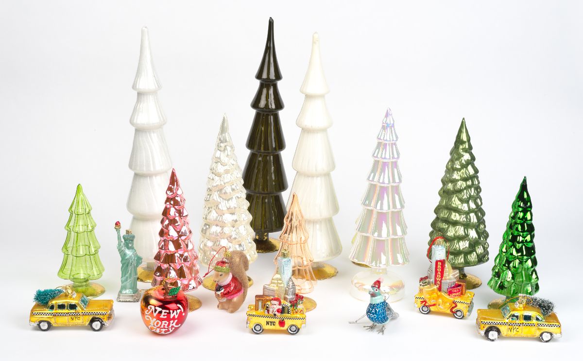 Arbres de Noël en verre et ornements devant un fond blanc.