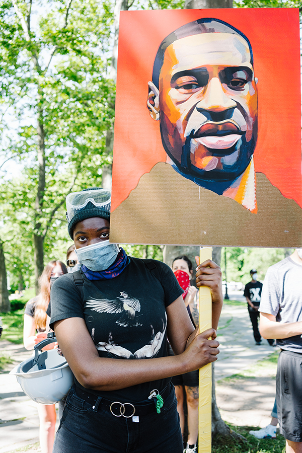 A person in a mask holds up a sign.