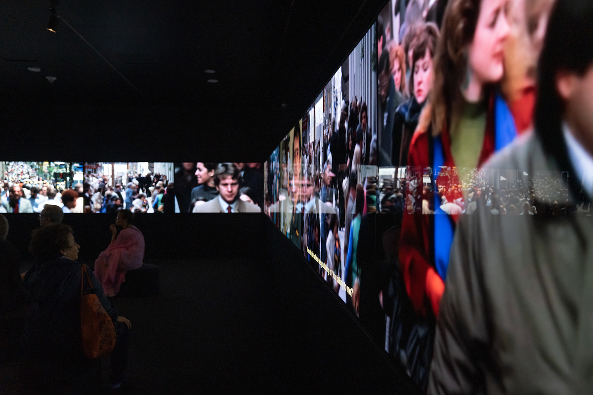 Installation view of You Are Here showing various video footage playing on a section of the 16-screen immersive film