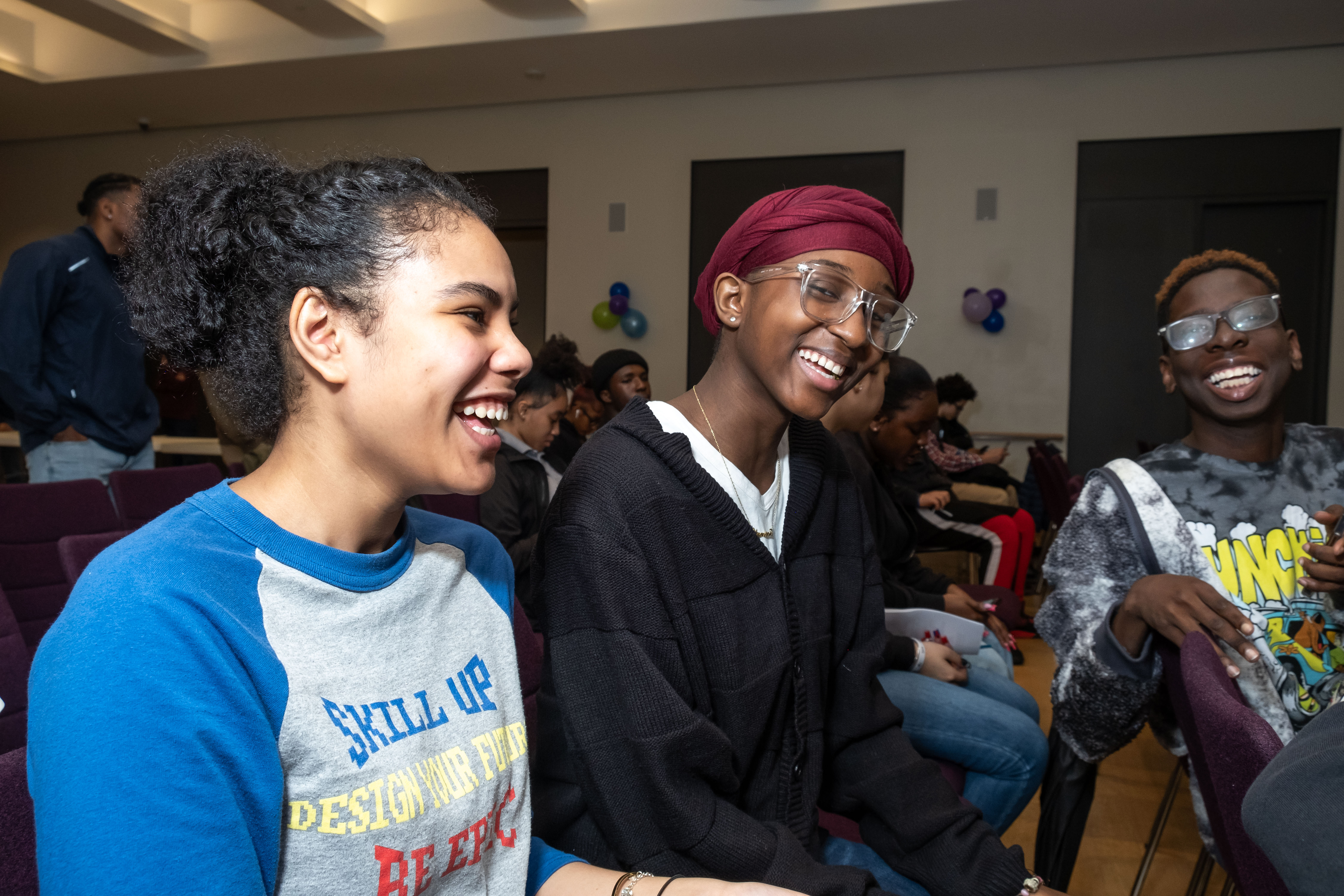 Three teenagers laugh together. 