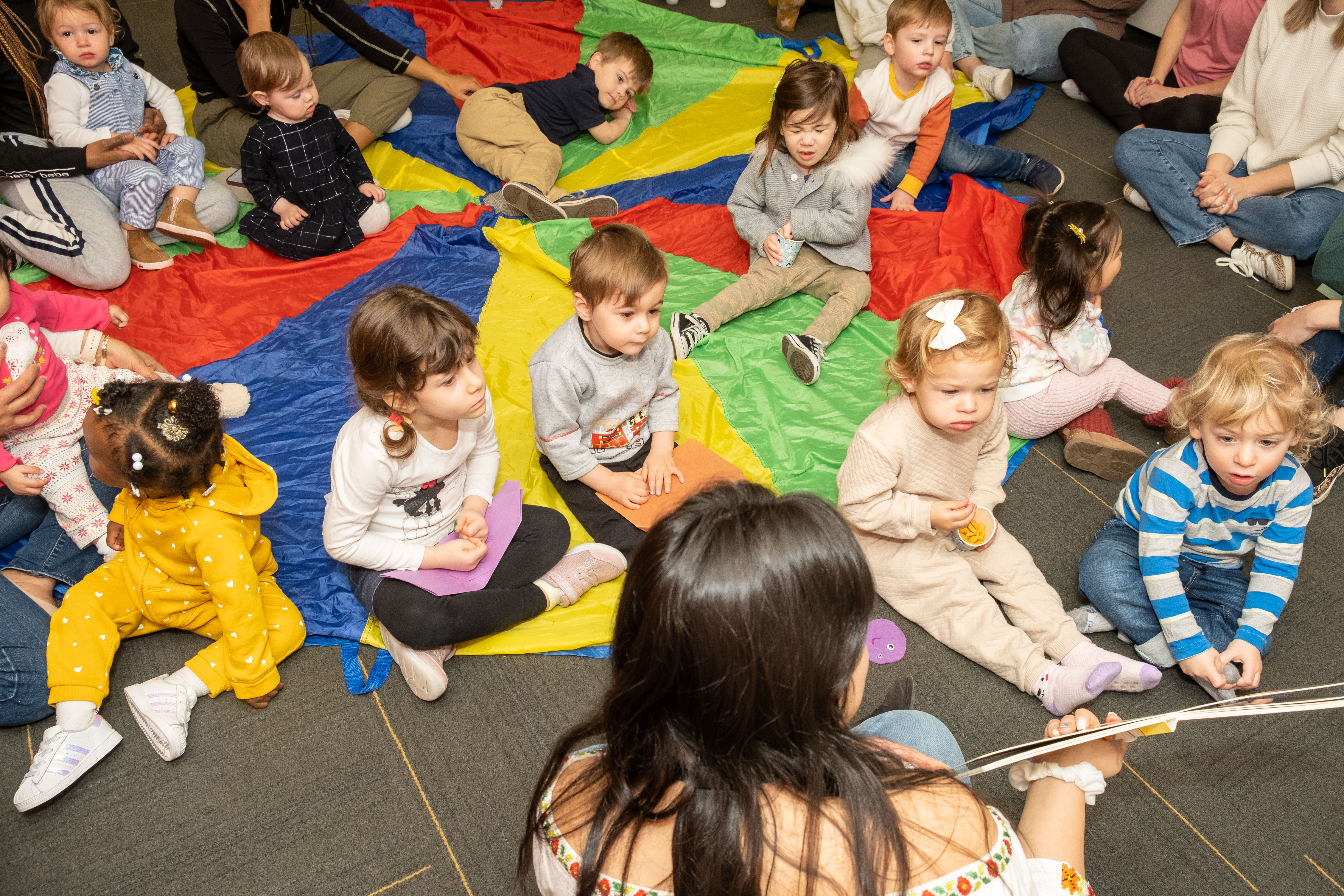 A woman reads a book to a group of children. 