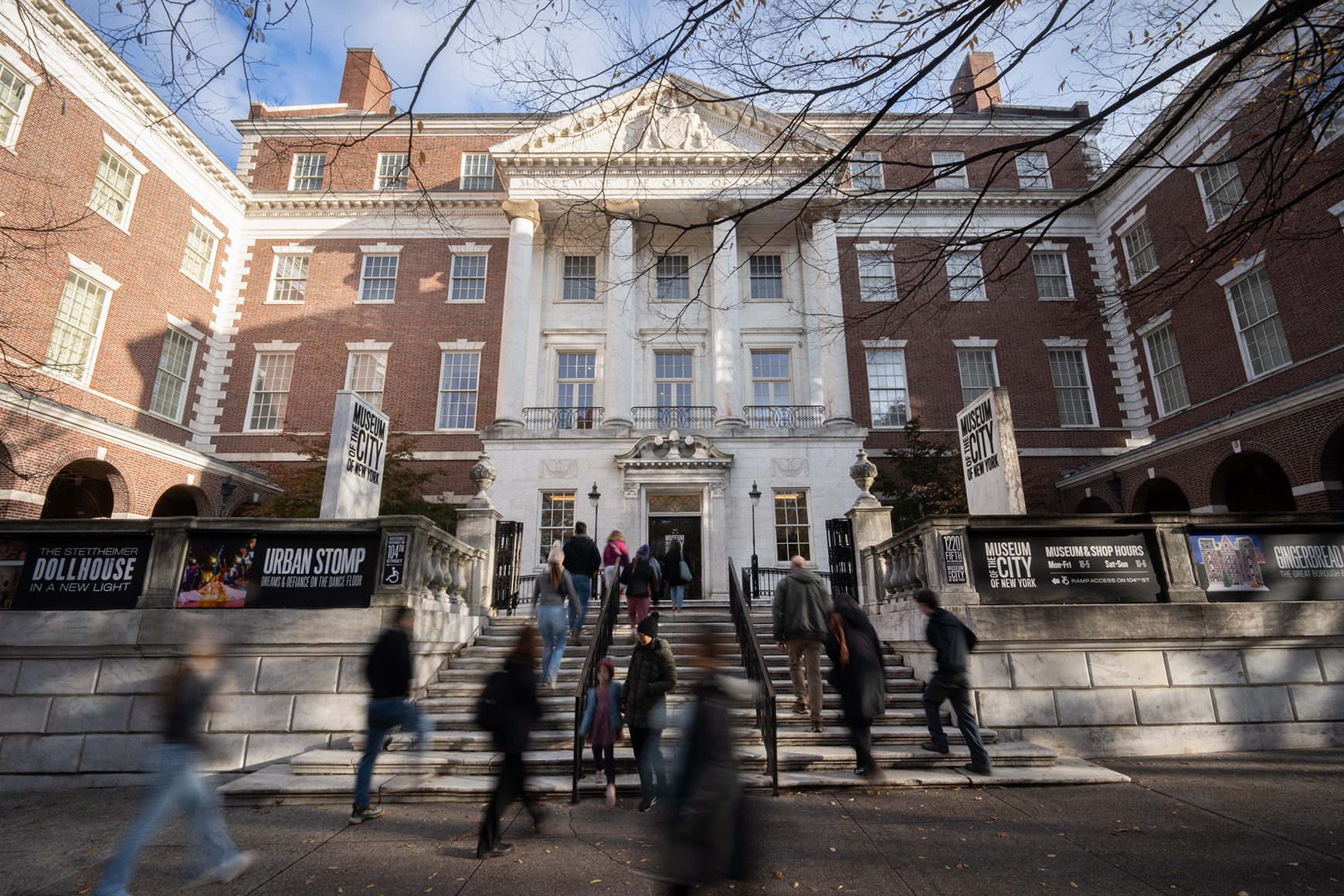 A crowd of visitors walks up the front steps toward the Museum's building