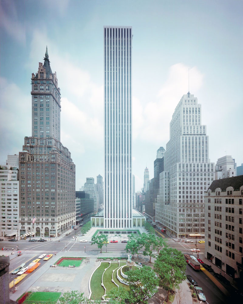 Un bâtiment domine ses voisins alors qu'il occupe un pâté de maisons à New York. Devant le bâtiment se trouve un parc