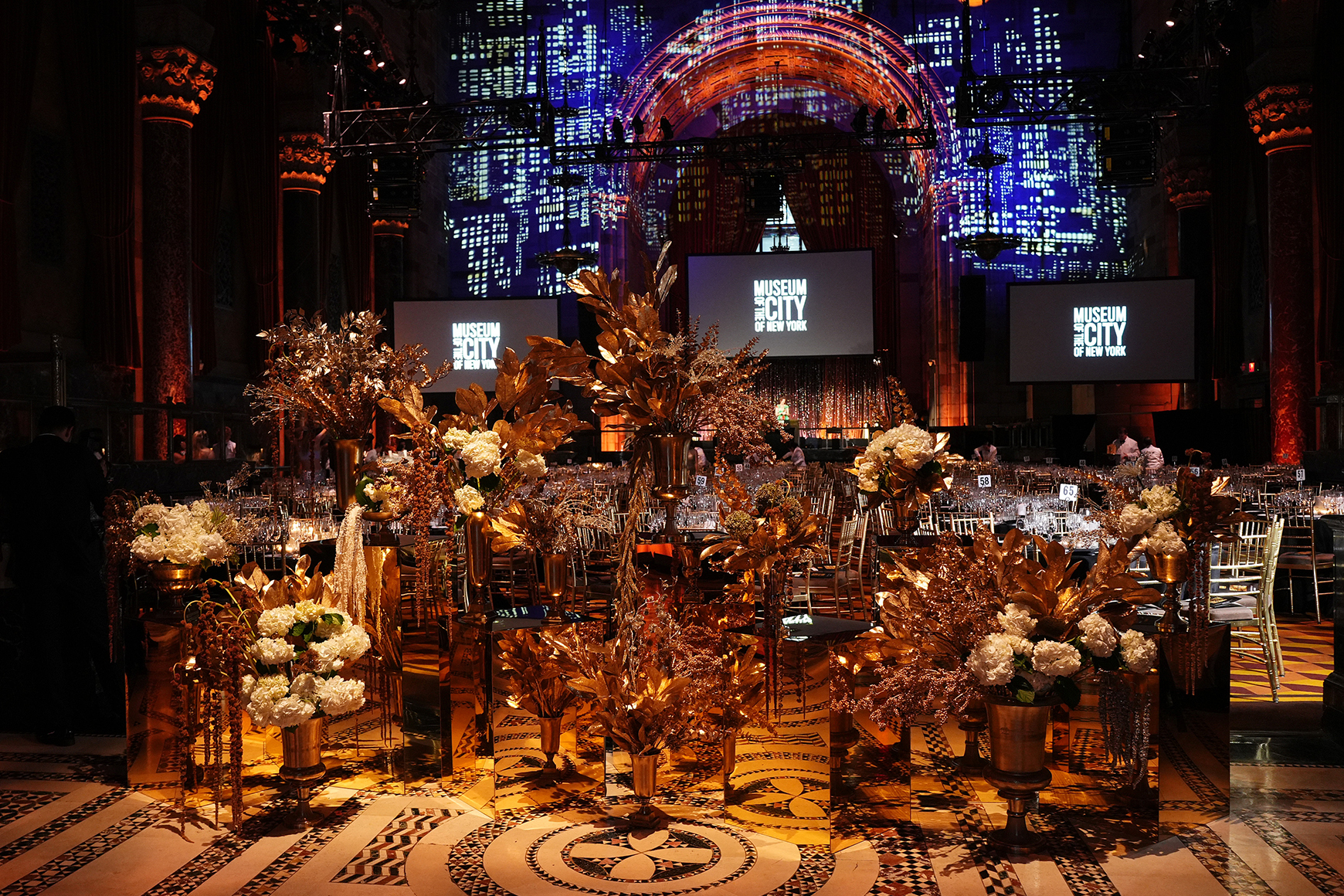 2025 Gotham Dreams Gala with tables in front of three screens showing the MCNY logo