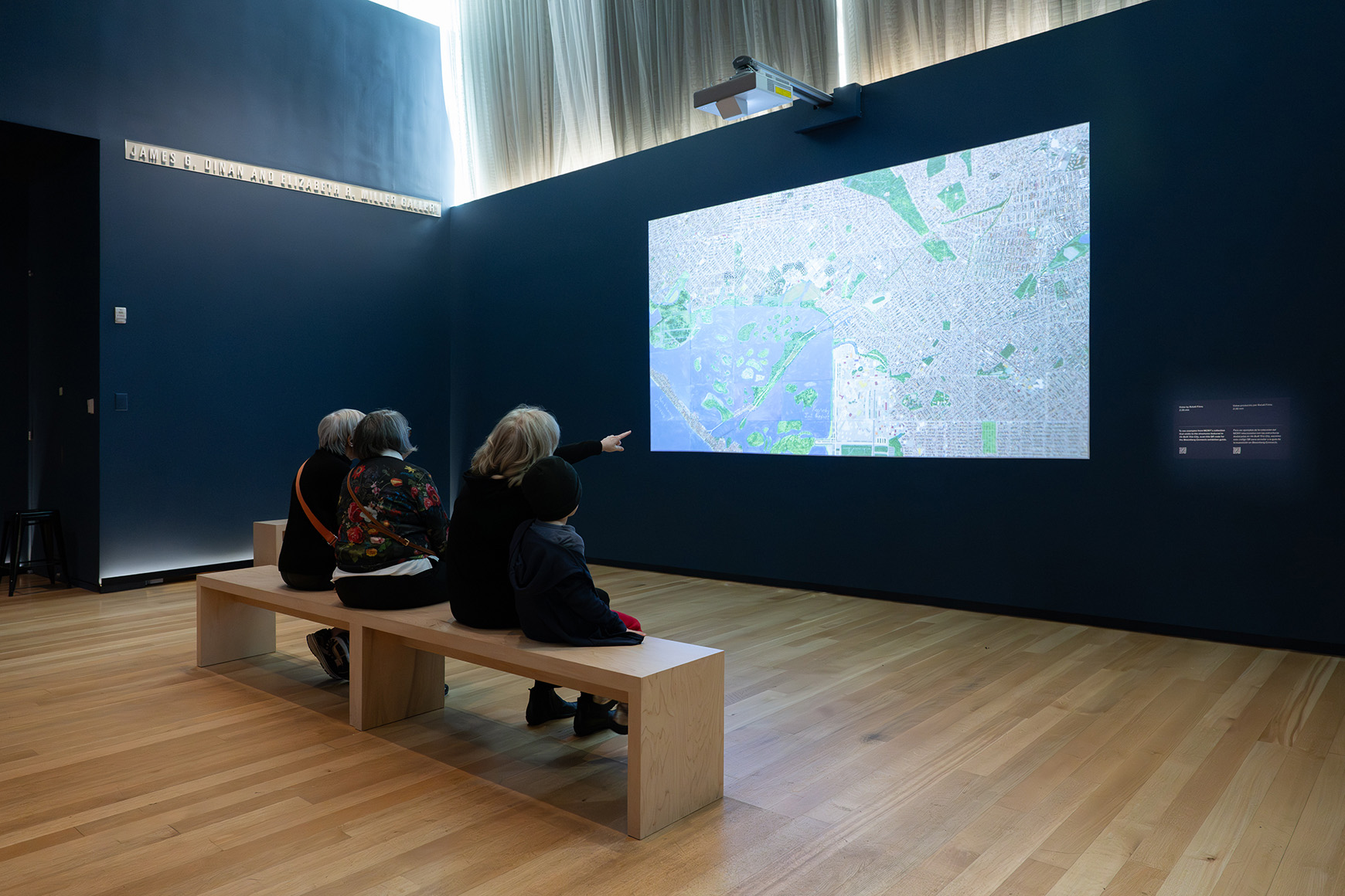A few people sitting on a bench watching a projected video
