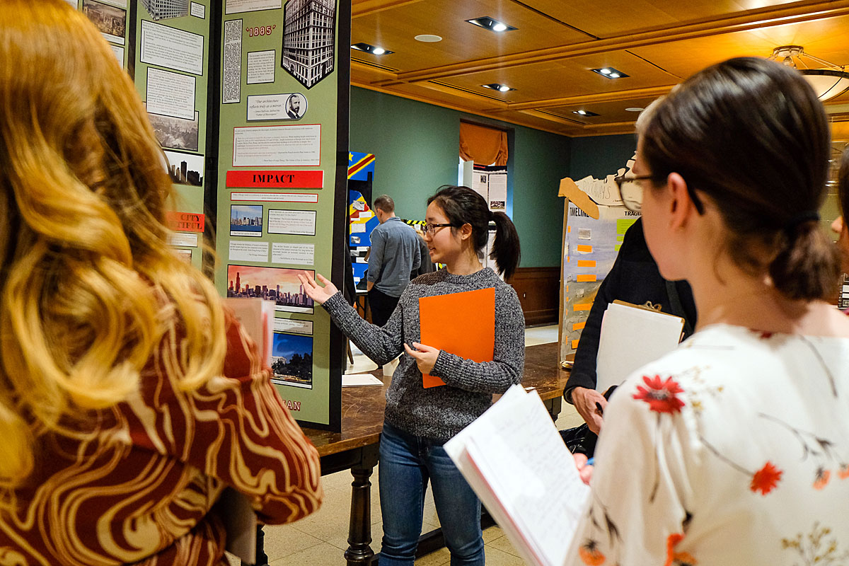 Un estudiante explica su tablero de proyecto mientras los jueces del Día de la Historia observan durante el Día de la Historia de la Ciudad de Nueva York 2019.